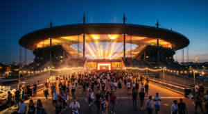 Foule de spectateurs se dirigeant vers l'entrée du Stade de France illuminé lors d'un concert en soirée d'été