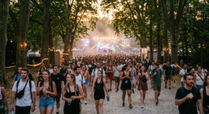 Foule de festivaliers marchant sous les arbres du Domaine National de Saint-Cloud en direction des scènes au coucher du soleil lors d'un festival d'été