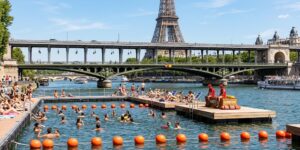 Baigneurs dans la Seine à Paris sur le site de Grenelle, zone délimitée par des bouées orange avec le pont de Bir-Hakeim et la Tour Eiffel en arrière-plan