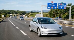 Tesla équipée du système FSD en cours d'essai sur une autoroute française avec un observateur de sécurité à bord, panneau autoroutier français visible en arrière-plan