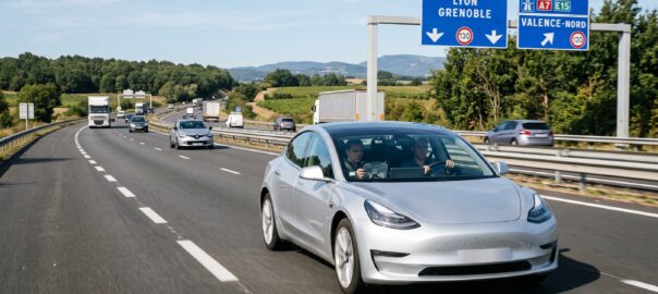 Tesla équipée du système FSD en cours d'essai sur une autoroute française avec un observateur de sécurité à bord, panneau autoroutier français visible en arrière-plan